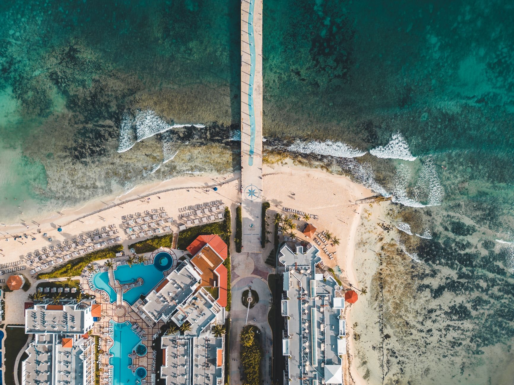 Captivating aerial view of Playa del Carmen's beachfront resort pier and turquoise sea.